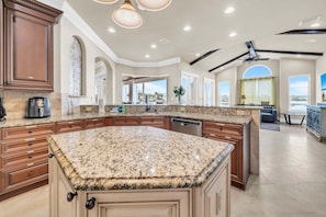 A spacious kitchen with granite countertops, wooden cabinets, and a large island. - 🦩Book Me Baby! Lakeside Luxury in Destiny East🦩 (Destin)