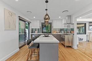 A modern kitchen with a central island, stainless steel appliances, and a pendant light. - Gladstone Luxury Spa Retreat Blue Mountains (Leura)