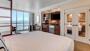 A hotel room with a large bed, a dining area with a view, a kitchen with modern appliances, and a balcony with a scenic view. - The Rose Premium Suite at MGM Signature (Las Vegas)