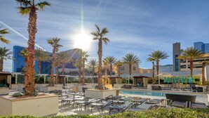 A rooftop pool area with lounge chairs, palm trees, and a view of city buildings. - The Rose Premium Suite at MGM Signature (Las Vegas)