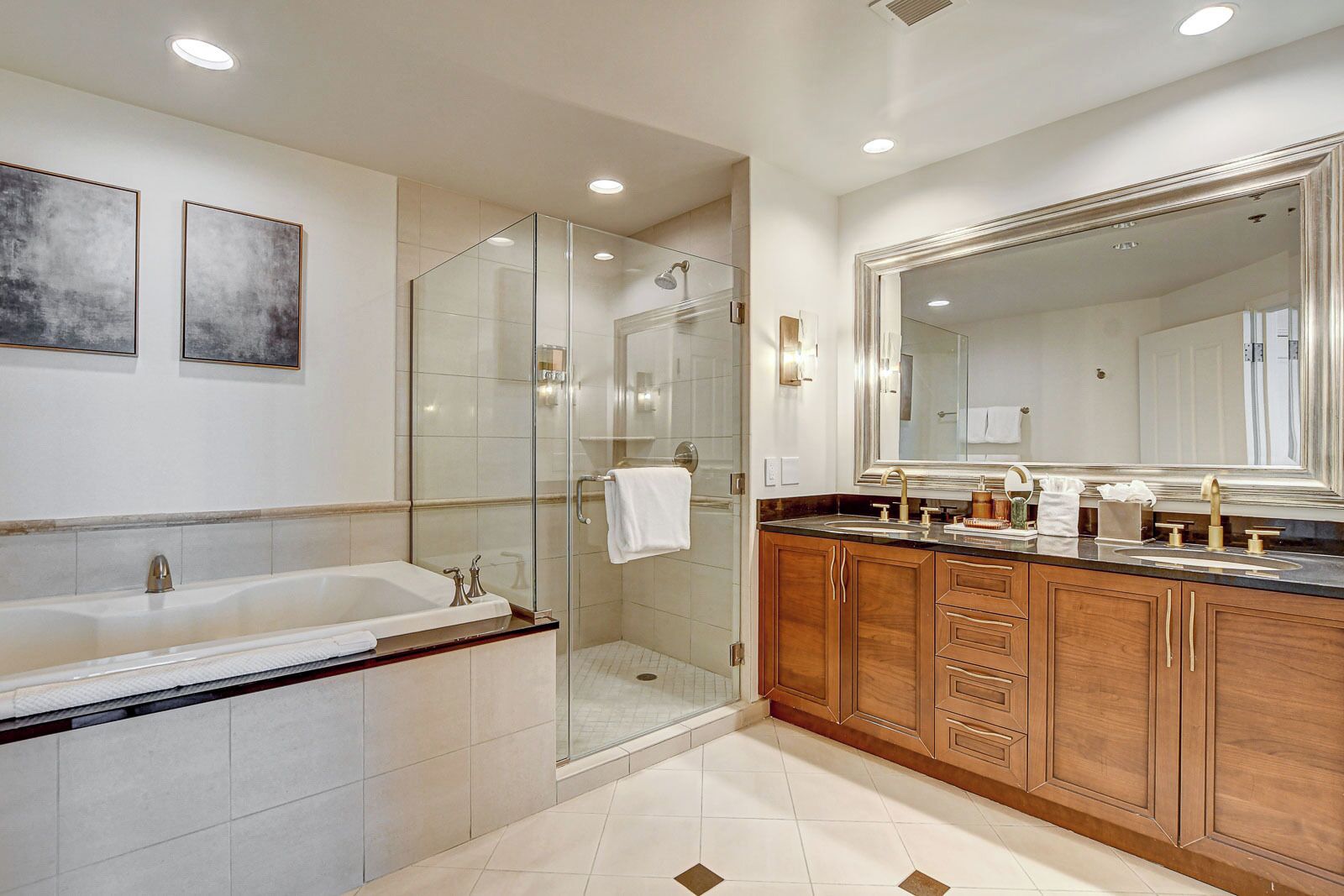 A modern bathroom with a glass-enclosed shower, a double sink vanity, and a large mirror.