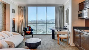 A hotel room with a large window, a bed, a dining table, a kitchen area, and a view of the cityscape. - The Rose Premium Suite at MGM Signature (Las Vegas)