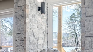 Una chimenea de piedra con un banco empotrado y una lámpara fijada a la pared.