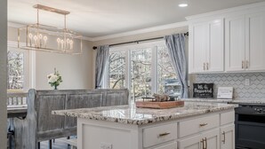 Una cocina con armarios blancos, encimera de mármol y una isla integrada.