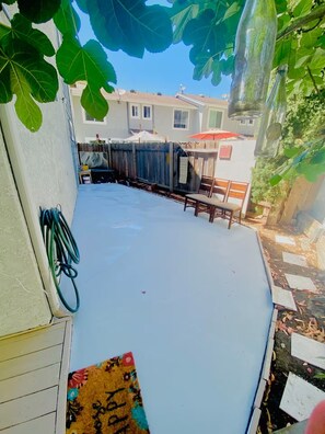A covered patio area with a white floor, a wooden fence, and a chair. - Artful Plant-Filled Beach Rtreat W/ Pvt Backyard and 8 minutes from the Beach!! (Laguna Niguel)
