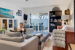 A living room with a sofa, a coffee table, a bookshelf, and a TV. - Artful Plant-Filled Beach Rtreat W/ Pvt Backyard and 8 minutes from the Beach!! (Laguna Niguel)