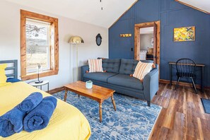 Ein Zimmer mit einem Bett, einem Schlafsofa, einem Holztisch und einem Sessel.
