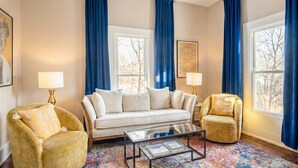 Un salon comprenant un canapé, deux fauteuils, une table basse et un tapis à motifs.