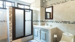 Ein modernes Badezimmer mit Duschabtrennung aus Glas, einem Waschbecken mit Spiegel darüber und einer Toilette.