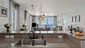 Een moderne keuken met granieten aanrechtbladen, een dubbele spoelbak en een eethoek met uitzicht op de oceaan.