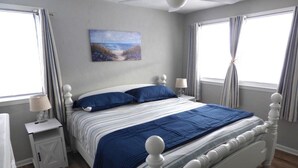 A bedroom with a bed, nightstands, a painting, and curtains. - Gardens Single-Family Home • Ocean Views • Dog Considered • FRIDAY TO FRIDAY (Ocean City)