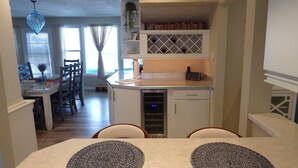 A kitchen with a 'DRIFT & DRINK' sign, a dining area with a table and chairs, and a view of the living room. - Gardens Single-Family Home • Ocean Views • Dog Considered • FRIDAY TO FRIDAY (Ocean City)