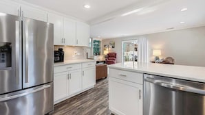 A modern kitchen with stainless steel appliances, white cabinetry, and a wooden floor. - Spacious Home 3BR Close to Beach Centrally Located (Myrtle Beach)