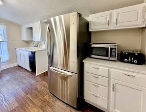 A kitchen with a stainless steel refrigerator, a microwave, and a toaster on the counter. - Charming Spacious 1870's ranch house, 4-bedroom, sleeps 11 adults, in Burnet TX. (Burnet)