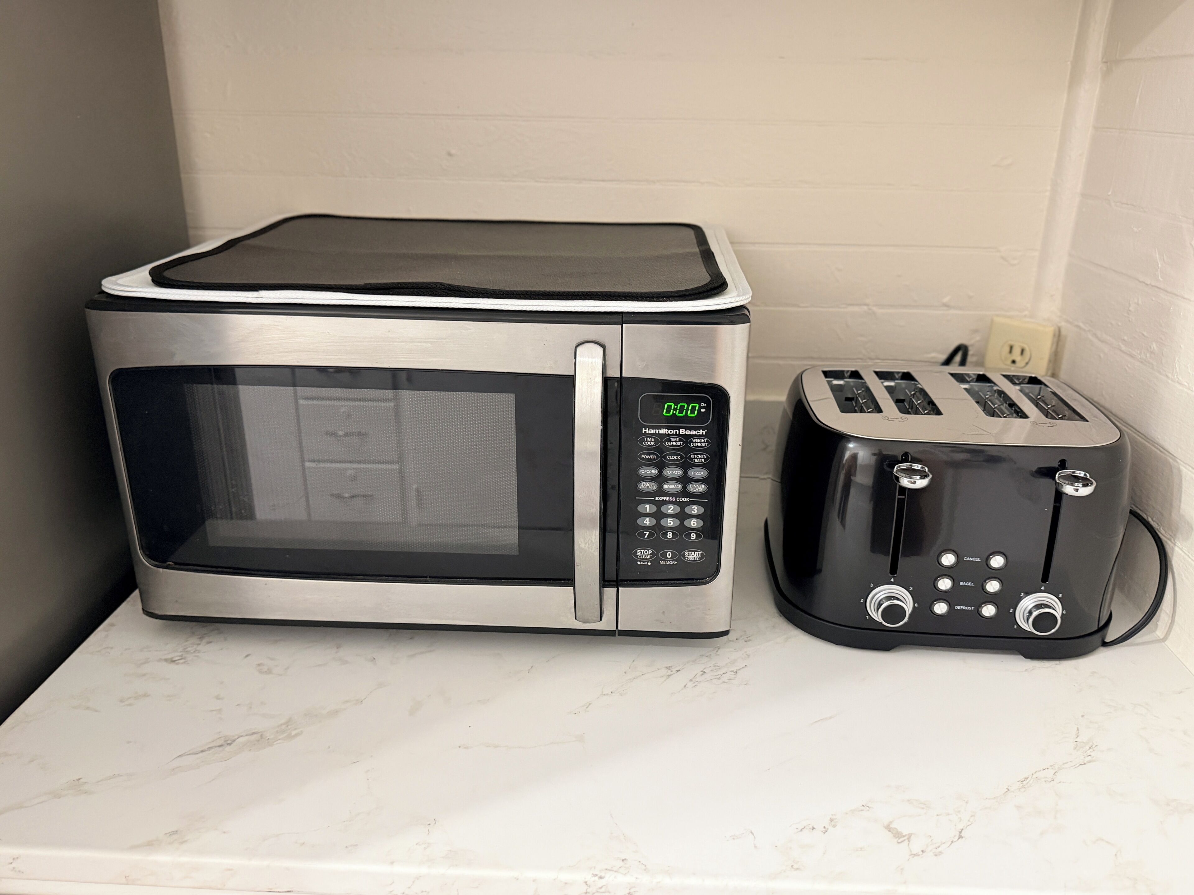 Une cuisine équipée d’un four à micro-ondes et d’un grille-pain, le tout posé sur un plan de travail en marbre.