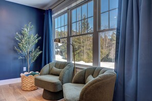 Ein Zimmer mit einem großen Fenster, einer Pflanze und zwei Sesseln.