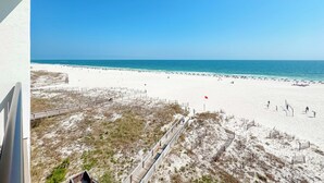 Ein Strand mit einem hölzernen Steg, Sandflächen und blauem Himmel.