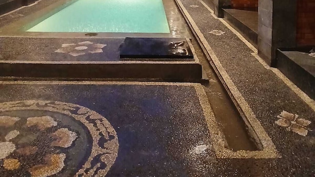 A spa area with a rectangular pool, benches, and a tiled floor. - Ulu Bali Homestay (Jimbaran)
