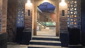 A building entrance with a wooden door and decorative panels, leading to a pool area. - Ulu Bali Homestay (Jimbaran)