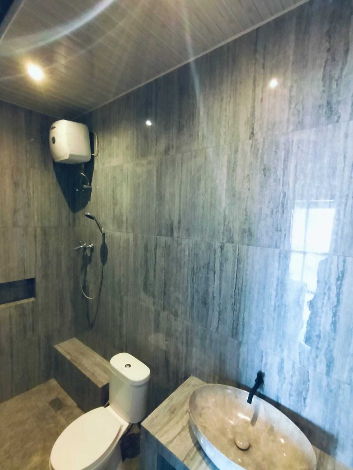 Un baño moderno con lavamanos de mármol, inodoro y ducha.