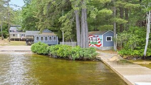 A lakeside property with a dock, a small building with a mural, and a house with a porch. - Long Lake Cabin: Shared Beach, Grill, Porch (Naples)