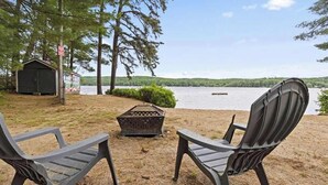 Two Adirondack chairs facing a lake with a dock and a shed in the background. - Long Lake Cabin: Shared Beach, Grill, Porch (Naples)