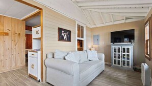 A cozy living room with a light-colored sofa, wooden cabinets, and a ceiling fan. - Long Lake Cabin: Shared Beach, Grill, Porch (Naples)