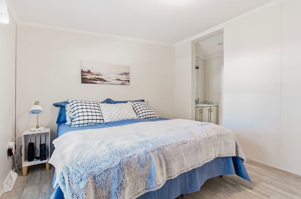 Une chambre à coucher avec un lit, une table de chevet, une lampe et un tableau au mur.