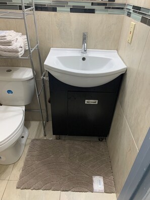 A bathroom with a white sink, a toilet, and a towel rack. - Charming and Comfortable Personalized (Miami Gardens)
