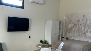 A modern bedroom with a bed, a TV, a wardrobe, and a small table with chairs. - Villa Uma with Private Jacuzzi and Secure Parking - 5 Minutes from the Sea (Puglia)