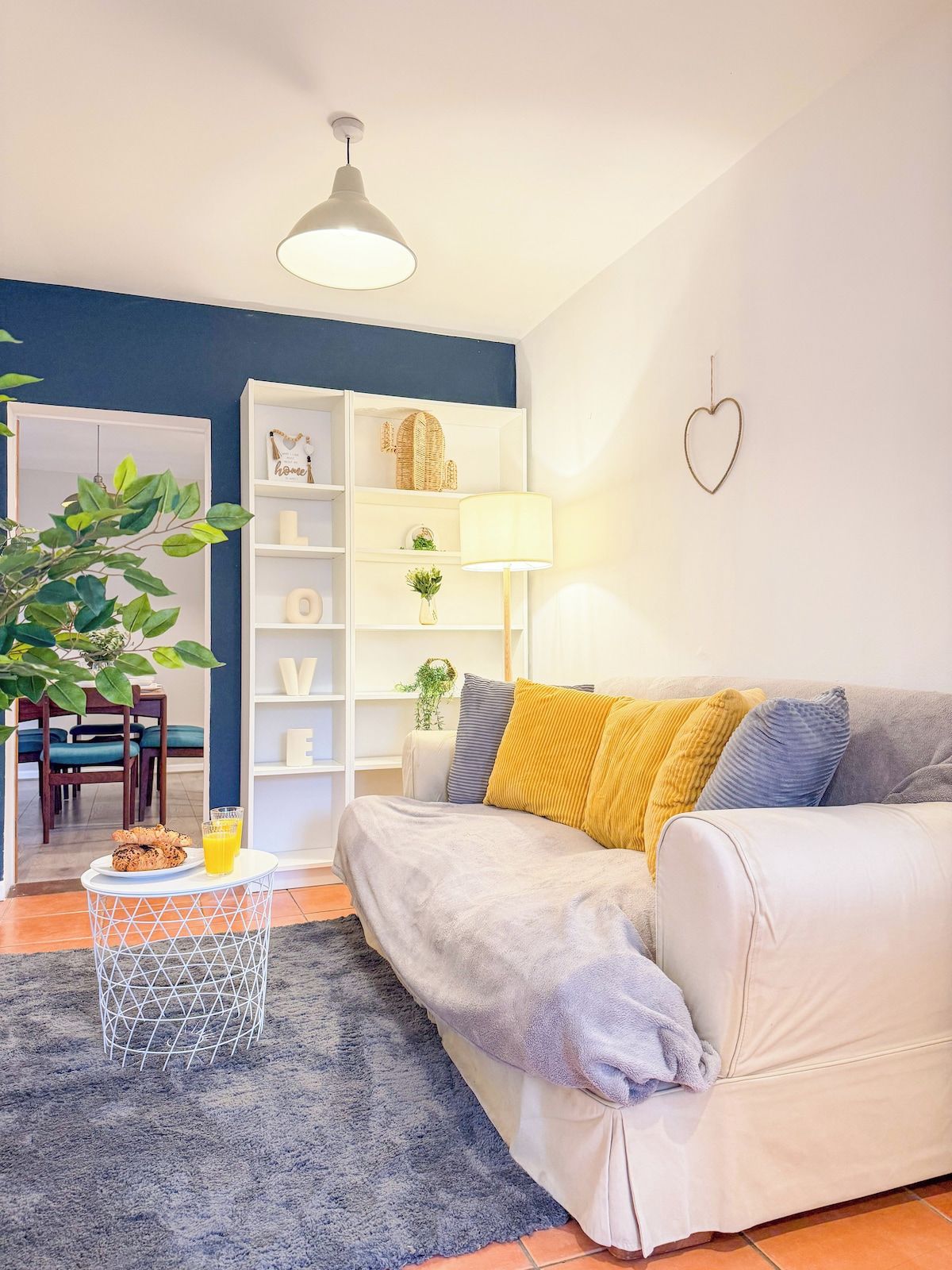 A living room with a sofa, a coffee table with a plant, and a bookshelf.