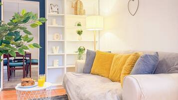 A living room with a sofa, a coffee table with a plant, and a bookshelf.