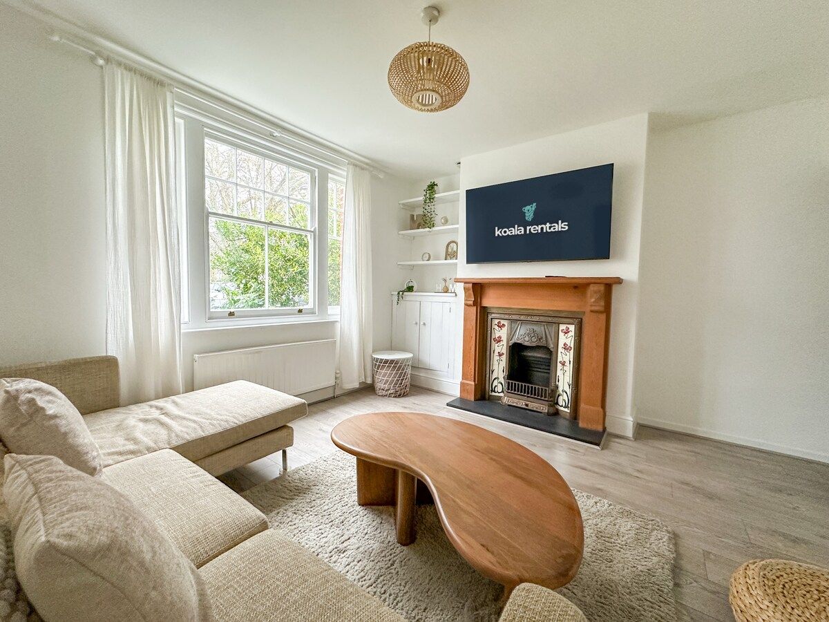 A living room with a sofa, a wooden coffee table, a fireplace, and a television mounted on the wall.