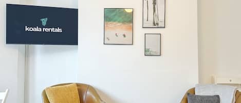 A living room with two leather armchairs, a flat-screen TV, and framed artwork on the wall.