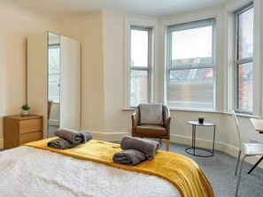 Une chambre d’hôtel avec un lit, une chaise, un bureau et une fenêtre avec des stores.