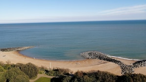 Ein Küstenstrand mit einem steinernen Wellenbrecher, blauem Himmel und weiter Ferne.