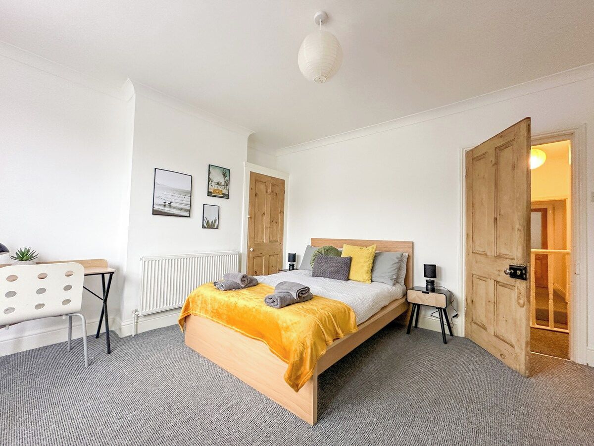 A bedroom with a bed, bedside tables, a desk, and a radiator.