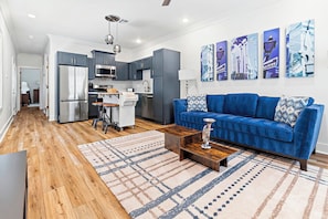A modern living room with a blue sofa, wooden coffee table, and patterned rug.