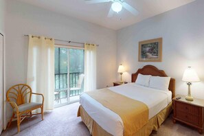 Une chambre d’hôtel avec un grand lit, une chaise, une table de chevet et un ventilateur de plafond.