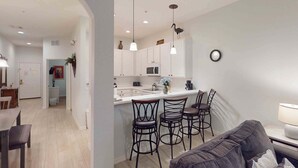 A modern kitchen with white cabinets, a central island with bar stools, and pendant lighting. - 2nd floor condo w/ shared pools, restaurant, near theme parks, gym, balcony (Davenport)