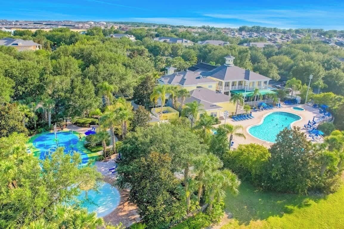 A residential area with multiple houses, a large swimming pool, and a well-maintained lawn.