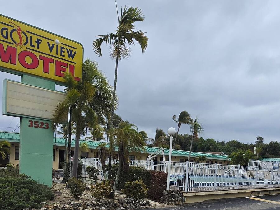 A motel with a prominent sign, a pool area, and a number 3523 building.