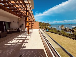 Ein Balkon mit Meerblick, eine Holz-Pergola und Sitzgelegenheiten im Freien.