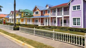 Une rangée de maisons colorées, dotées de balcons et précédées d’une clôture blanche.