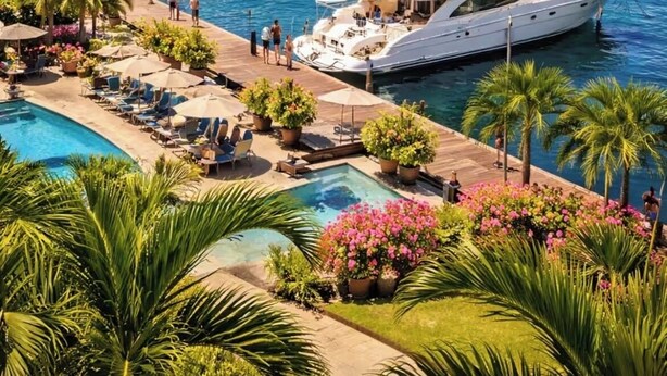Un port de plaisance où sont amarrés de nombreux yachts, une piscine et une végétation luxuriante.