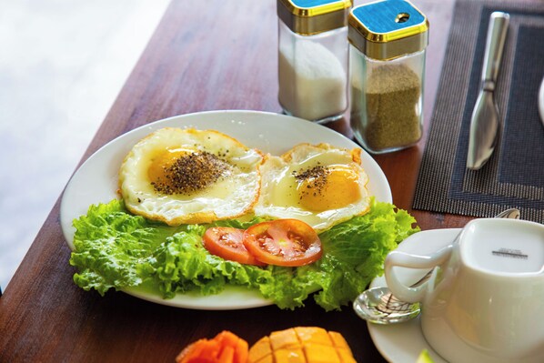 A plate of eggs, lettuce, and tomatoes on a wooden table with salt and pepper shakers and a cup of coffee. - Bridge Front Inn Ella (Ella)