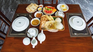 Une table à manger dressée avec des assiettes, des bols et une variété d’aliments, notamment du riz, des légumes et des œufs.