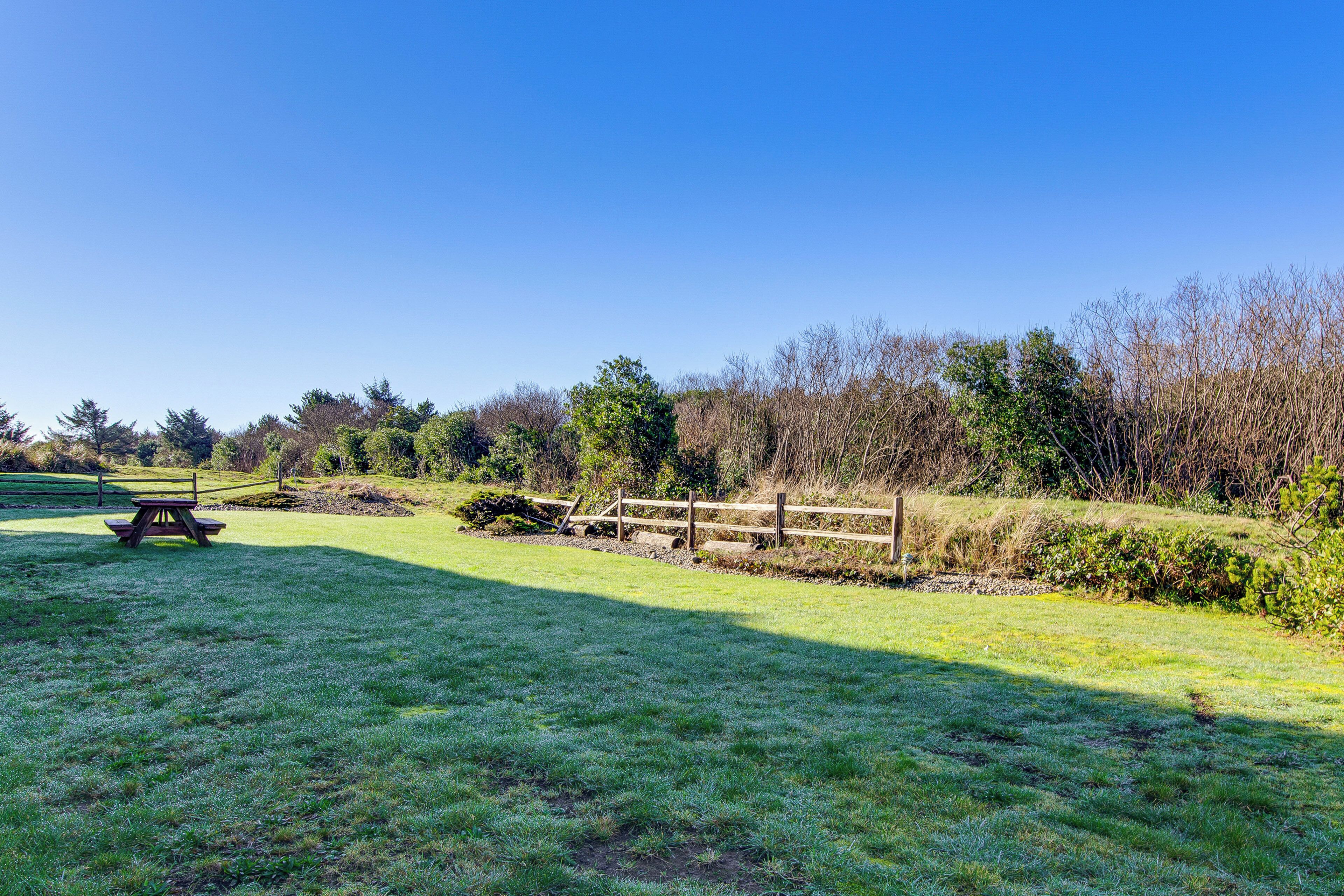 A grassy field with a wooden fence and picnic table.