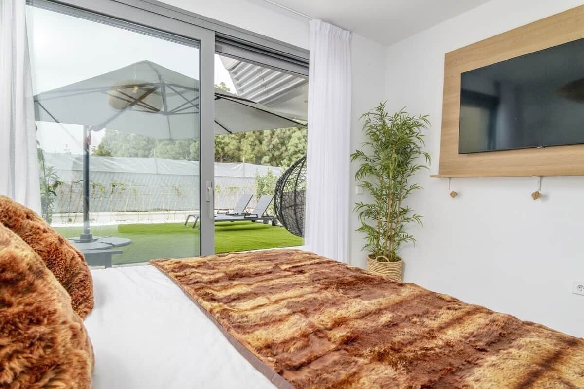 Une chambre moderne avec une grande fenêtre, un téléviseur à écran plat, une plante en pot et un tapis en fourrure.