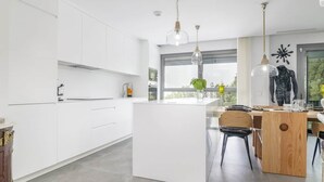 Een moderne keuken met witte kasten, een centraal eiland en hanglampen.